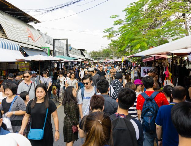 Tourists and locals in a crowded main walkway at Chatuchak Market